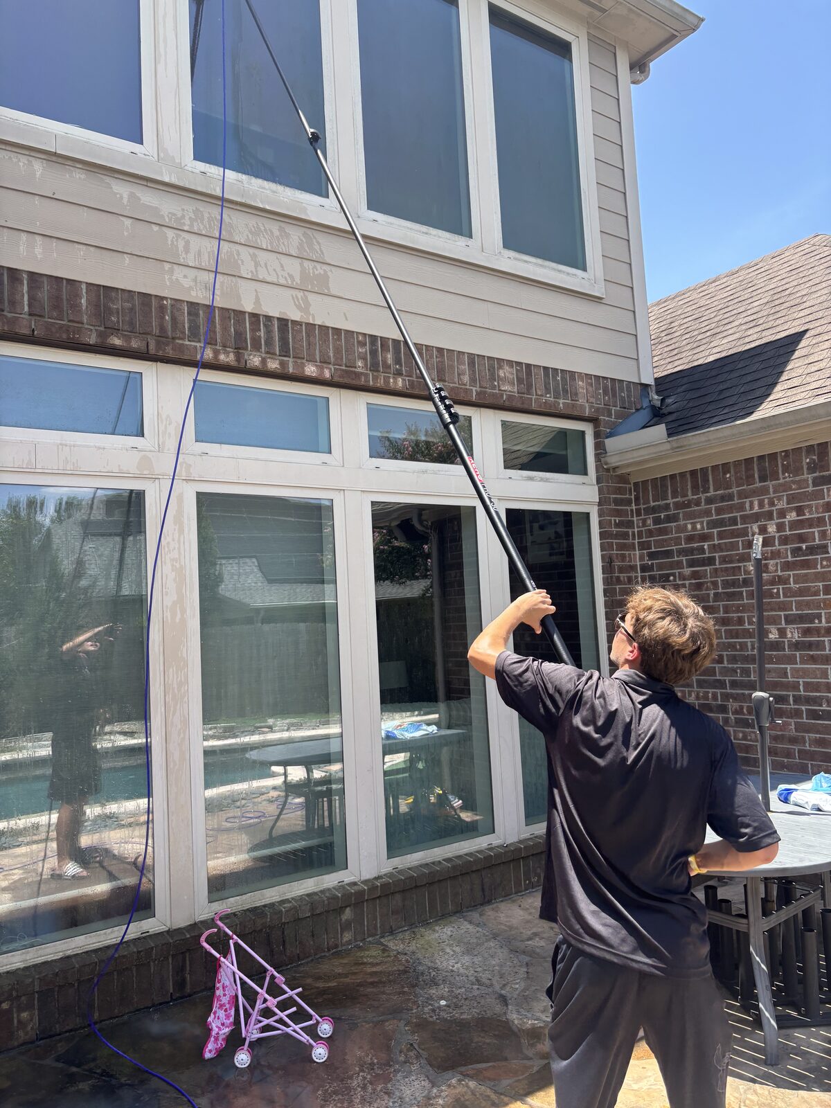 Technician cleaning second-story windows with a water-fed pole